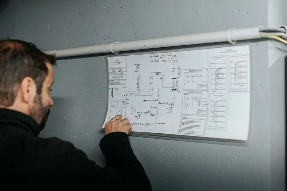 Chauffagiste vérifiant la conformité et la sécurité des installations sur un plan