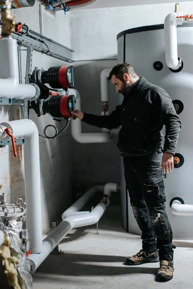 Technicien chauffagiste travaillant sur une installation de chauffage collectif